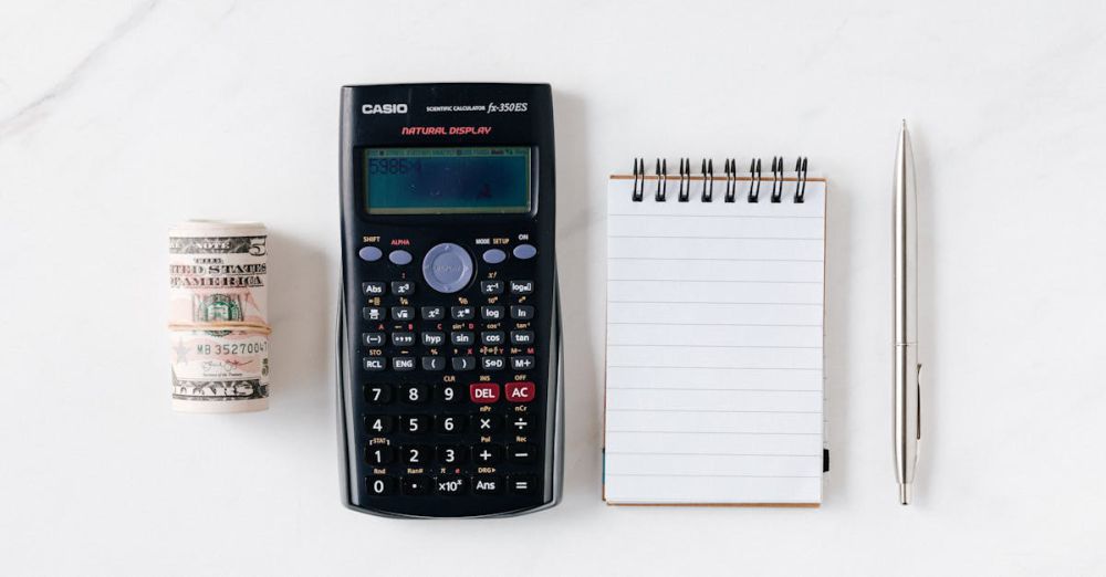 Budget Springs - Top view of financial tools including a calculator, notepad, pen, and rolled cash on a white background.