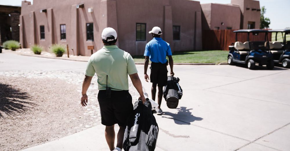 Couples Courses - Two golfers walking towards a golf cart carrying bags on a sunny day.