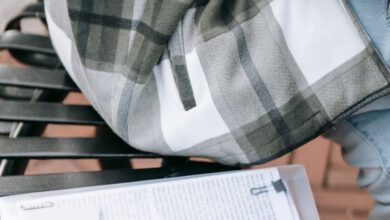 Public Courses - A young woman in a plaid shirt studies from papers on a city bench outdoors.