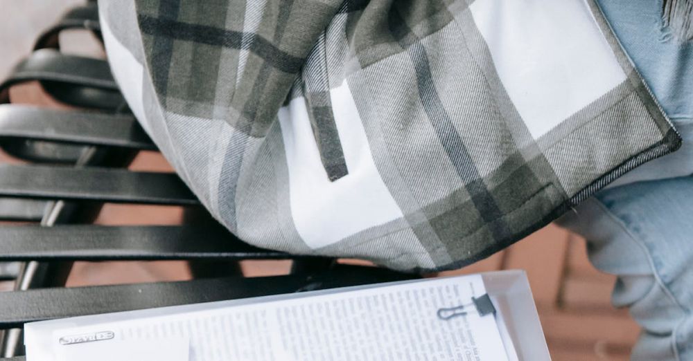 Public Courses - A young woman in a plaid shirt studies from papers on a city bench outdoors.