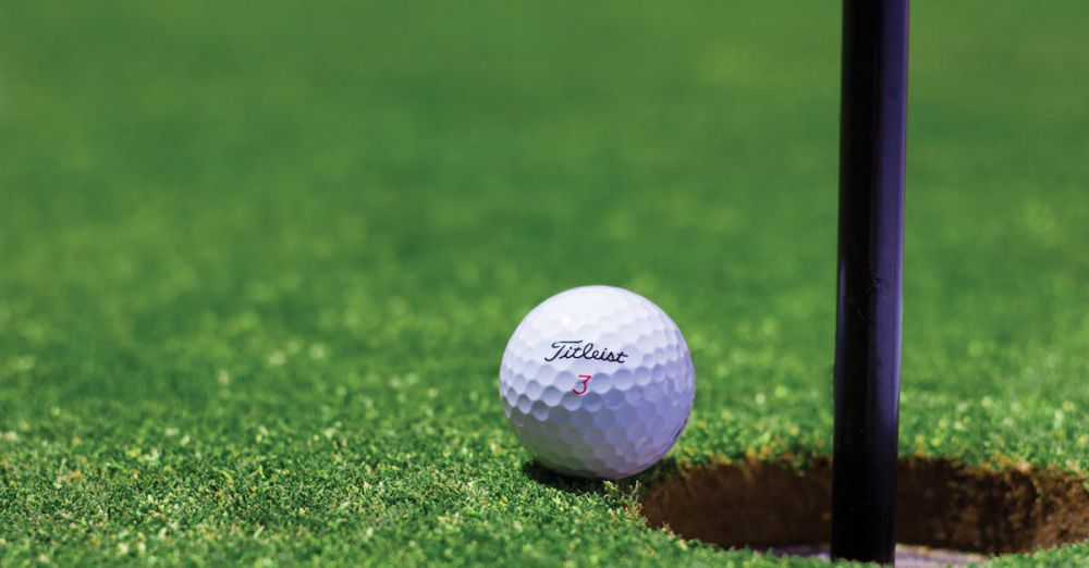 Golf Vacation - Close-up of a golf ball near a hole on a vibrant golf green, capturing the moment of near success.