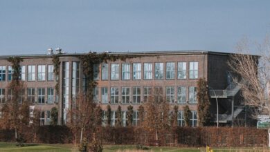 Corporate Golf - A modern building with large windows viewed from a golf course featuring a grassy field and trees.