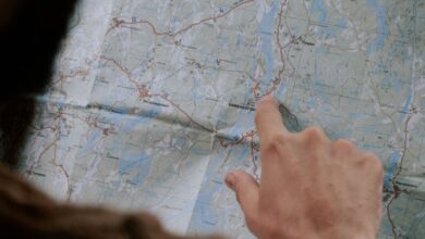 Scenic Routes - Close-up of a person's hand pointing at a map inside a car, emphasizing travel.