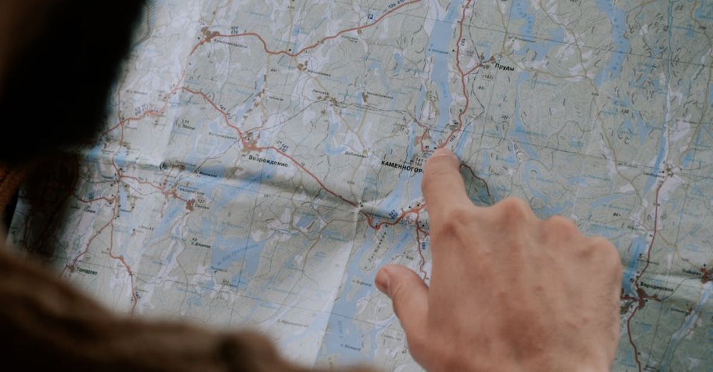 Scenic Routes - Close-up of a person's hand pointing at a map inside a car, emphasizing travel.