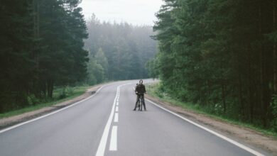 Cycling Trip - A lone cyclist rides along a misty road surrounded by lush forests in Russia.