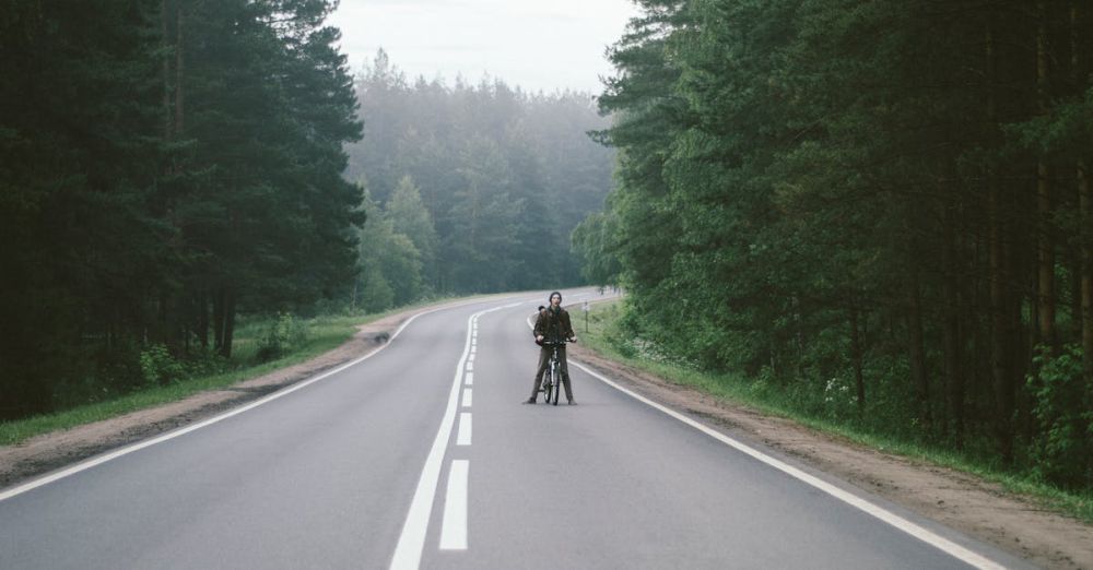 Cycling Trip - A lone cyclist rides along a misty road surrounded by lush forests in Russia.