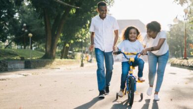 Family Cycling - Happy family teaching their child to cycle on a sunny day outdoors.