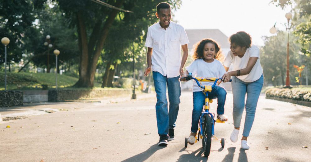 Family Cycling - Happy family teaching their child to cycle on a sunny day outdoors.