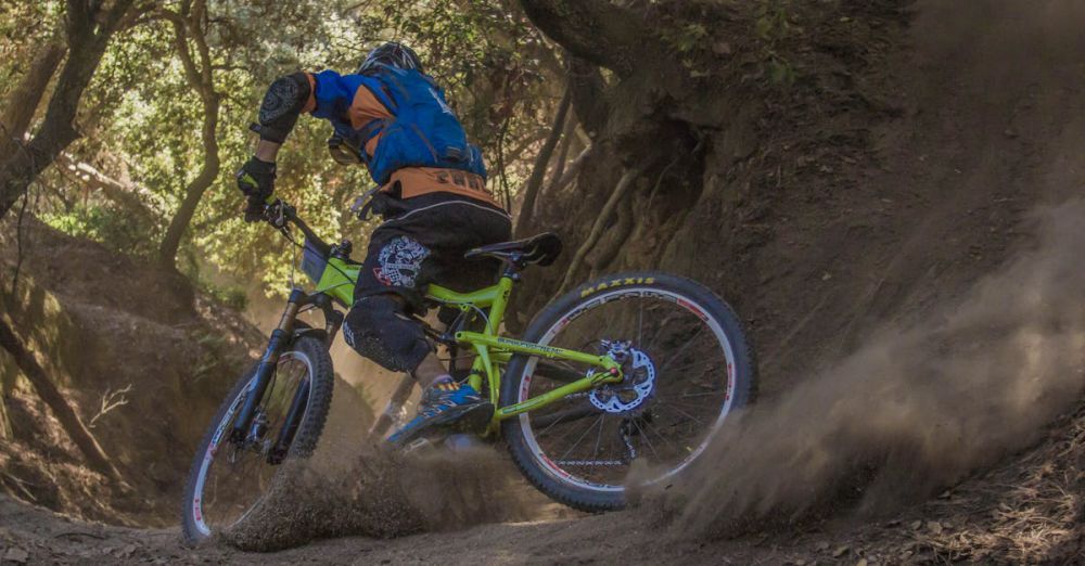 Mountain Biking - Mountain biker navigates a challenging off-road trail, kicking up dust in a forest setting.