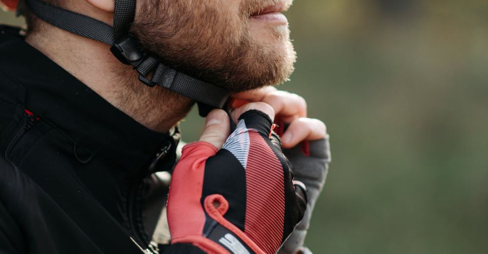 Cycling Safety - Side profile of a cyclist outdoors fastening his helmet with protective gear.