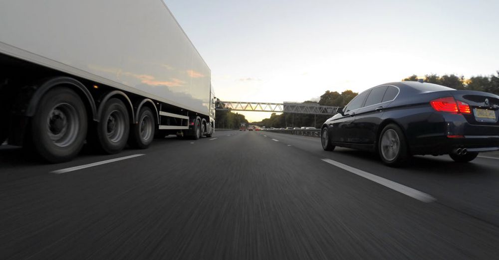 Long-Distance Routes - Cars and a truck speed along a highway under the clear sky, showcasing transportation dynamics.