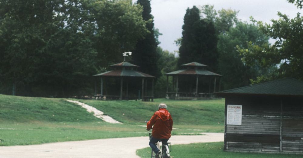 Solo Cycling - Person riding a bicycle down a winding path in a lush green park with cloudy skies.