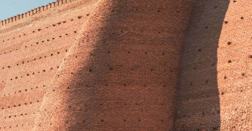 History Cycling - A cyclist rides past the ancient walls of the Ark Fortress in Bukhara, Uzbekistan.