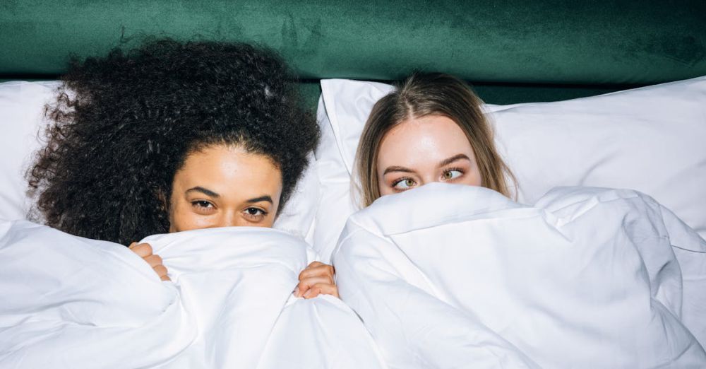 Best Time - Two young women sharing joyful, cozy moments in bed, embracing happiness and friendship.