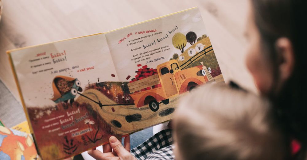 Storytelling - A mother and toddler sharing a story from an illustrated children's book indoors.