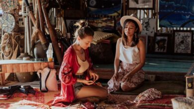 Cultural Immersion - Two women crafting souvenirs in a vibrant Thai shop, surrounded by art and textiles.