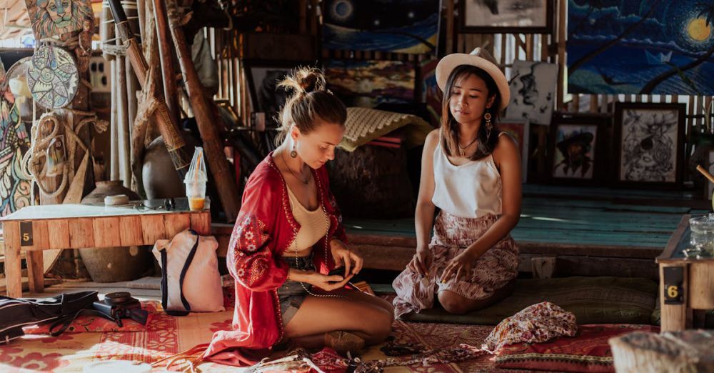 Cultural Immersion - Two women crafting souvenirs in a vibrant Thai shop, surrounded by art and textiles.