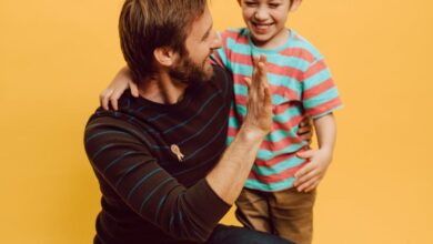 Best Time - Father and son sharing a joyful high five indoors against a vibrant yellow background.