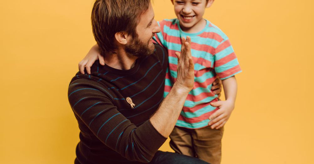 Best Time - Father and son sharing a joyful high five indoors against a vibrant yellow background.