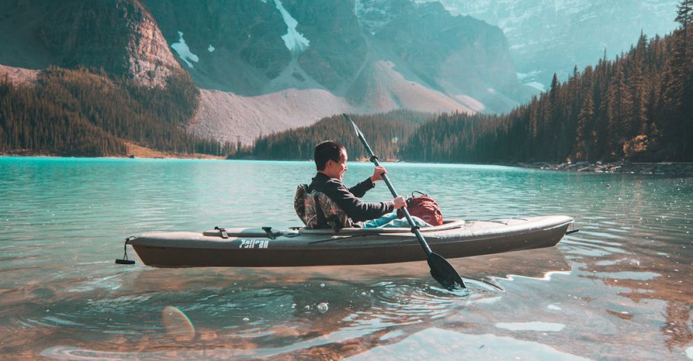 Wildlife Kayaking - A lone kayaker paddles on the serene waters of Moraine Lake with stunning mountain scenery in Banff, Alberta.