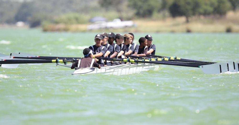 Kayaking Skills - Energetic rowing team practicing on a serene lake during daylight showcasing teamwork and coordination.