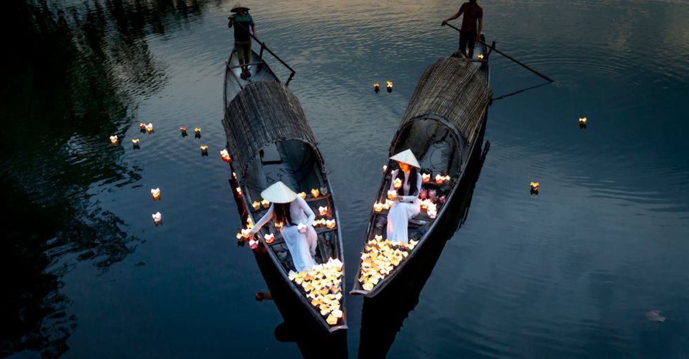 Night Paddling - Drone view of anonymous elegant female putting candle lanterns on river water from boats against male partners in evening