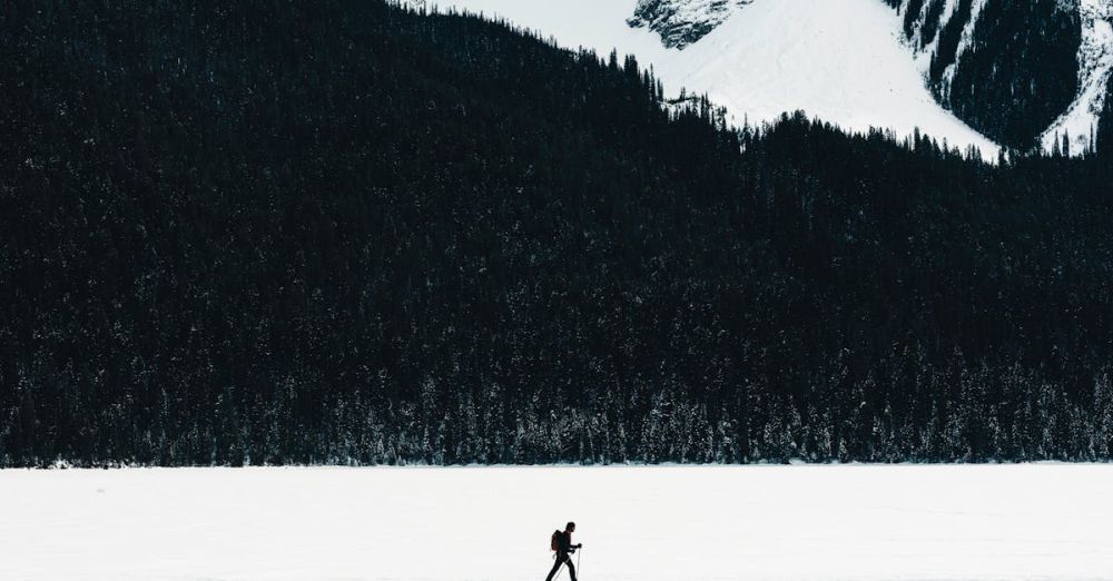 Wildlife Snowshoeing - Lone hiker crossing a snowy field with rugged mountains in Field, BC, Canada.