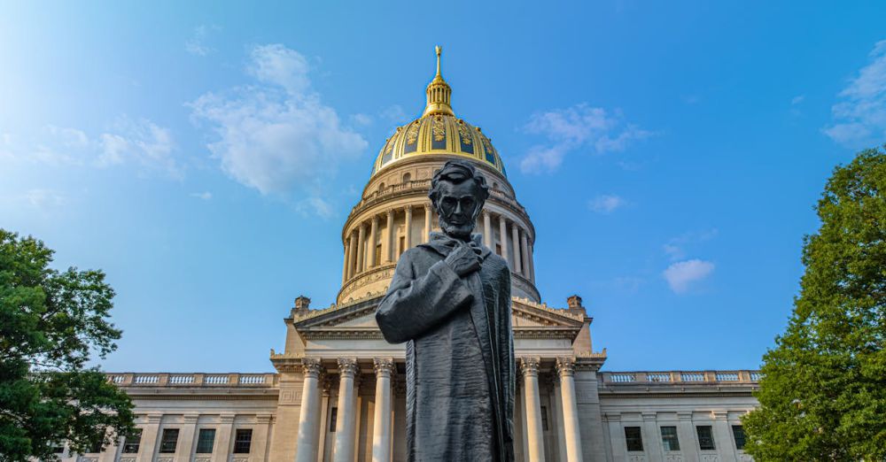 Photography Locations - Facade of the West Virginia State Capitol building with a statue of Abraham Lincoln in the foreground under clear blue skies.