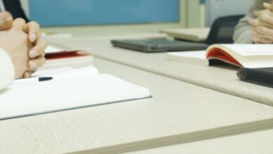 Preparation - Close-up of a professional meeting setup with hands, laptops, and notebooks on a wooden desk.