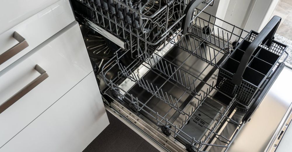 Dishwasher - A clean and empty stainless steel dishwasher open in a modern kitchen setting.