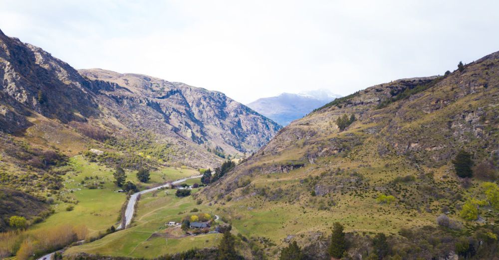 Scenic Routes - Breathtaking aerial view of mountainous landscape in New Zealand, showcasing lush green valleys and winding roads.