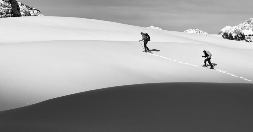 Remote Snowshoeing - Two hikers trekking uphill in a snowy mountain landscape, capturing the essence of winter adventure.