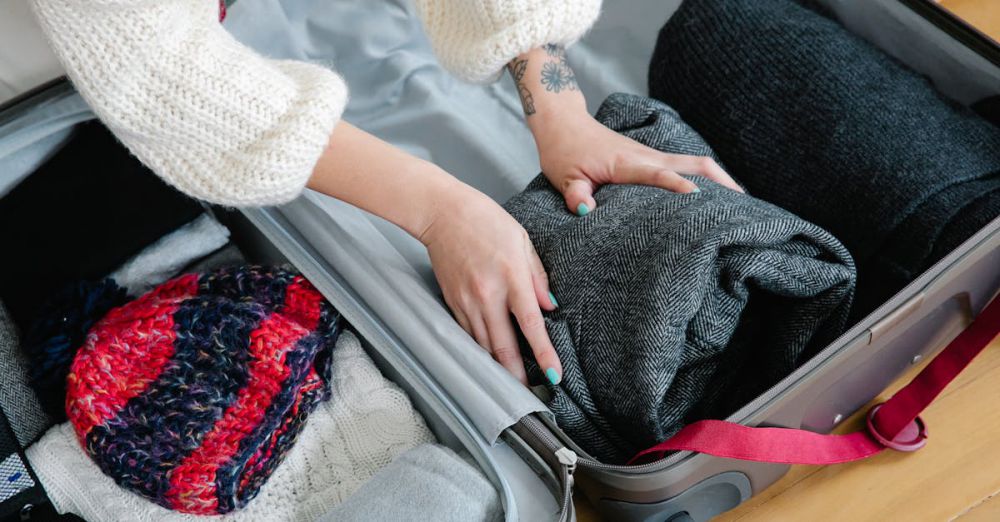 Winter Trip - Close-up of hands packing cozy sweaters and knitwear into a suitcase for a trip.