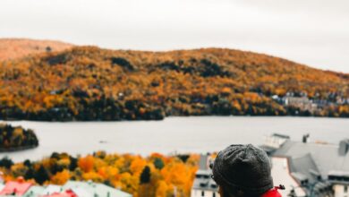 Quebec Trails - Person in red jacket enjoying fall view in Mont-Tremblant, Canada with a warm beverage.