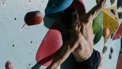 Climbing Skills - Shirtless male rock climber scales colorful indoor climbing wall with focus and agility.