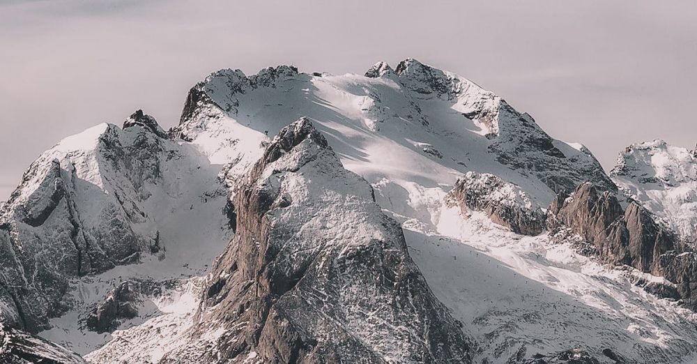 Year-Round Ice Climbing - A breathtaking view of a snow-capped mountain range under a clear sky, capturing winter's beauty.