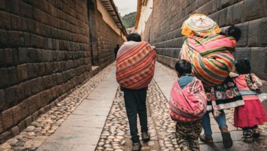 Family Routes - Family in colorful ponchos walking down a historic alley, showcasing South American culture.