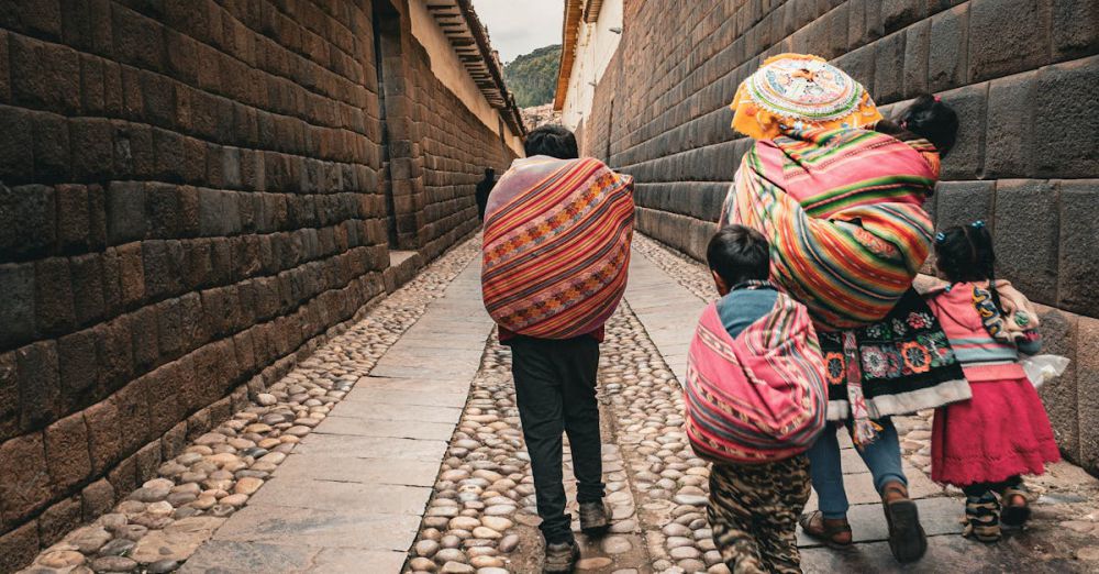 Family Routes - Family in colorful ponchos walking down a historic alley, showcasing South American culture.