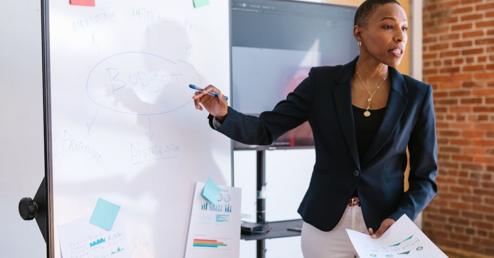 Training Tips - Professional businesswoman explaining budget strategy on a whiteboard during a meeting.