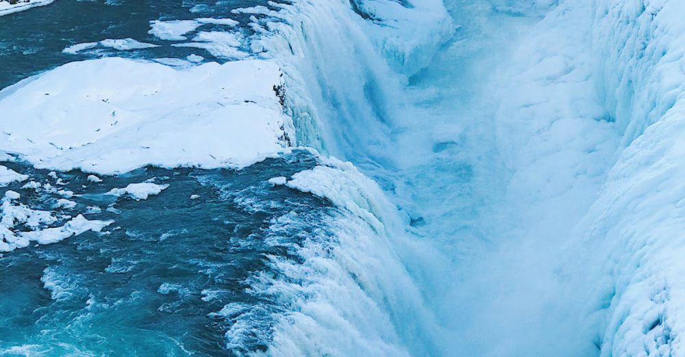 Winter Waterfalls - Stunning view of a frozen waterfall cascading through a snowy Icelandic gorge, capturing winter's icy beauty.