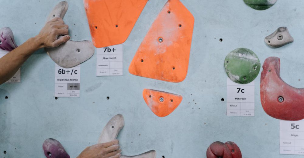 Fitness Routes - Hands gripping colorful climbing holds on an indoor climbing wall, highlighting strength and technique.