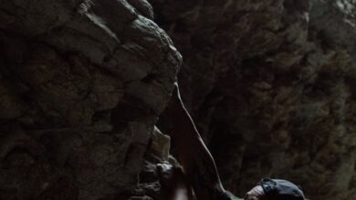 Solo Climbing - A determined man rock climbing on a rugged cliff face outdoors.