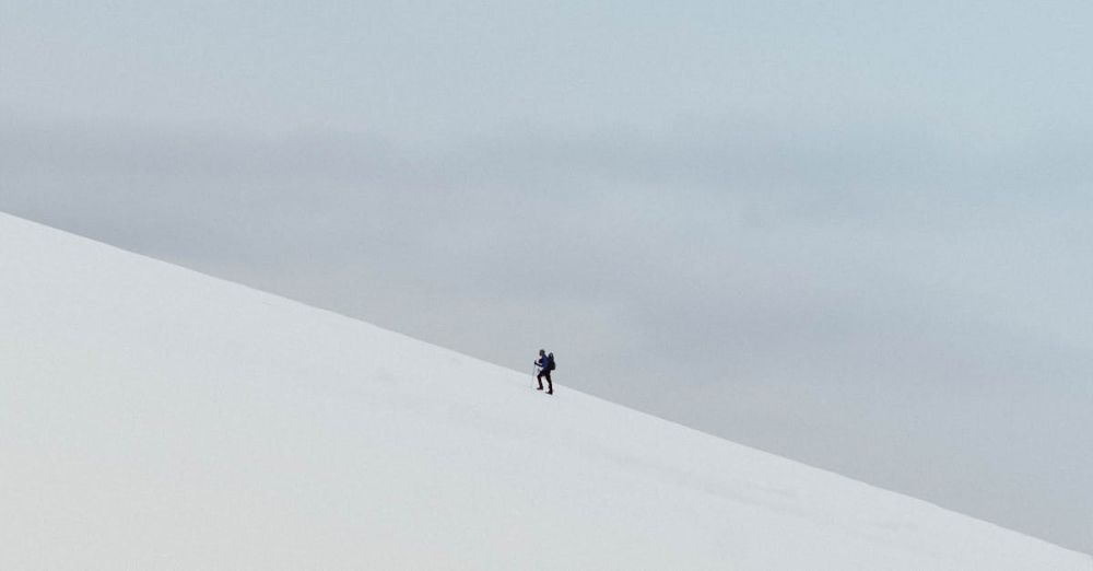 Extreme Cold Climbing - A lone hiker ascends a snowy slope in Norway's remote wilderness, showcasing winter adventure.