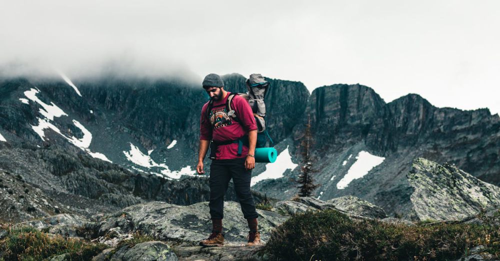 BC Glacier Tours - A man hiking on rocky terrain in the British Columbia mountains, with a foggy backdrop. Ideal for adventure and travel themes.