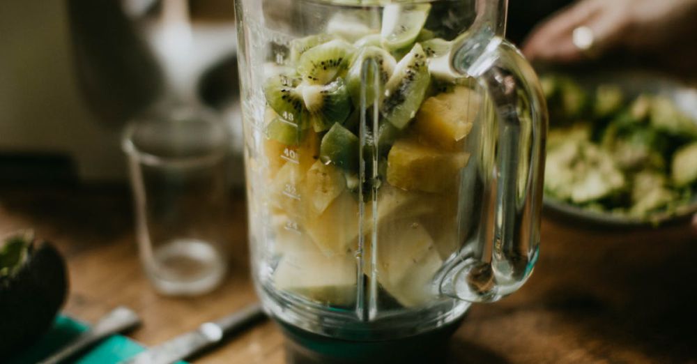 Blender - Close-up of a blender with kiwi and pineapple chunks ready to make a smoothie in a cozy kitchen setting.