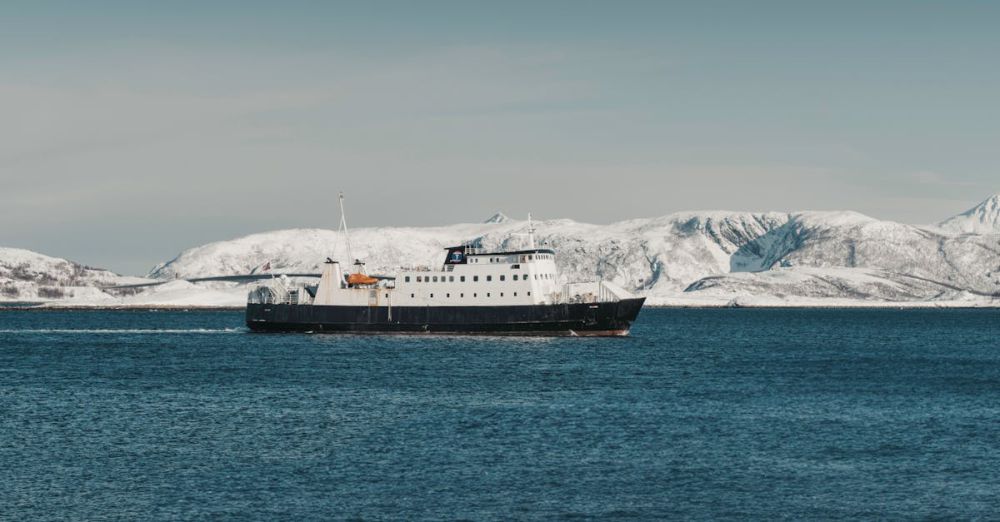 Glacier Navigation - A ferry navigates through a Norwegian fjord with snow-covered mountains in the background.