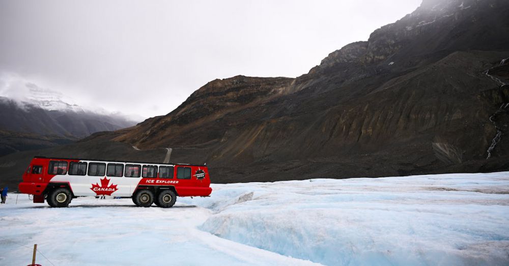 Alberta Glacier Tours - Red Ice Explorer bus on Athabasca Glacier under cloudy sky in Jasper National Park.