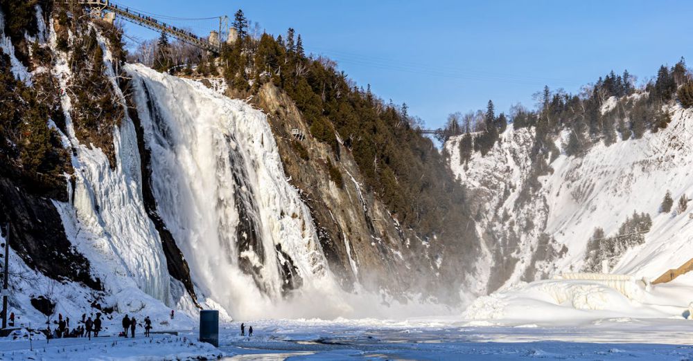 Quebec Glacier Tours - Frozen waterfall cascading down a snowy mountain under a blue sky, perfect for winter nature photography.