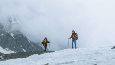 Couple Glacier Tours - Two hikers traverse a snowy mountain landscape, enveloped in fog, embodying adventure and exploration.