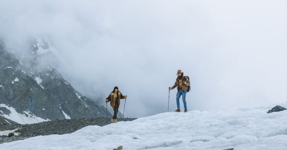 Couple Glacier Tours - Two hikers traverse a snowy mountain landscape, enveloped in fog, embodying adventure and exploration.